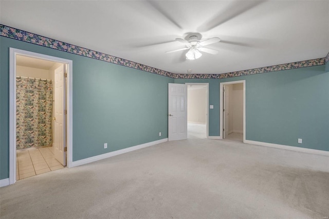 carpeted spare room featuring baseboards and ceiling fan