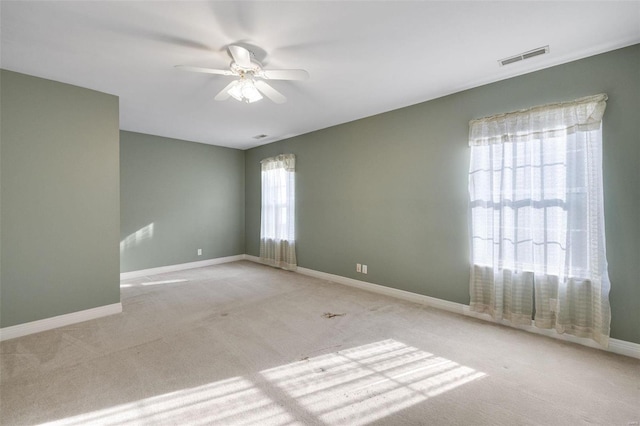 spare room with visible vents, carpet flooring, a ceiling fan, and baseboards