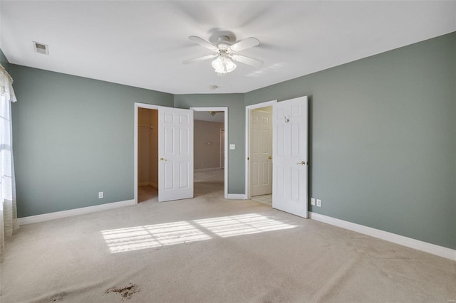 unfurnished bedroom featuring visible vents, baseboards, ceiling fan, a spacious closet, and light carpet