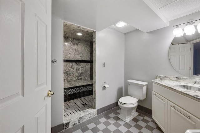 bathroom with vanity, a shower stall, toilet, and baseboards