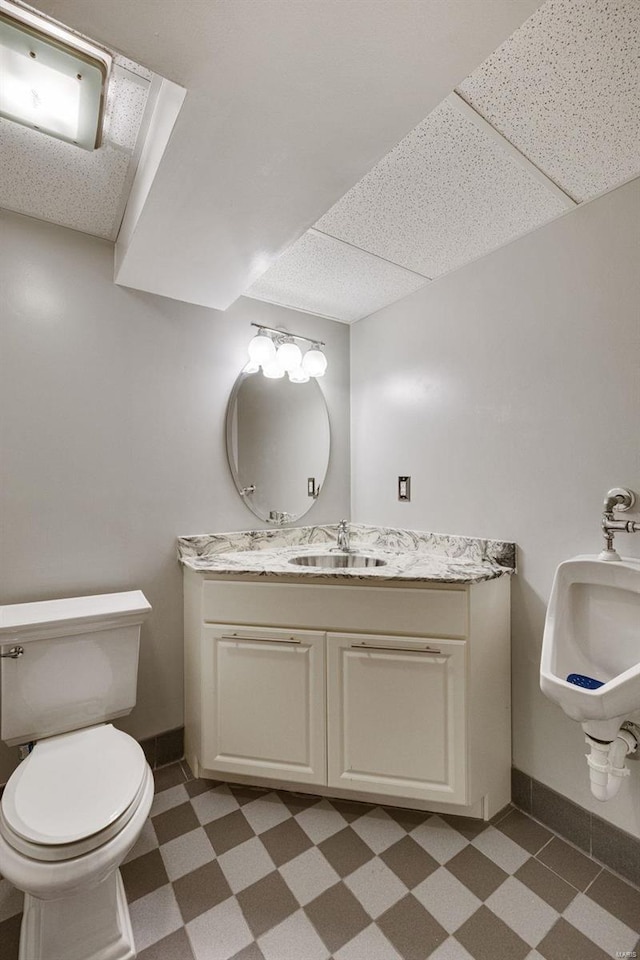 bathroom with tile patterned floors, toilet, a paneled ceiling, baseboards, and vanity