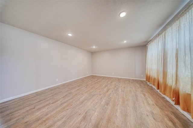 unfurnished room with recessed lighting, a textured ceiling, baseboards, and light wood-style floors