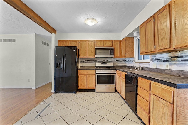 kitchen featuring black appliances, dark countertops, visible vents, and a sink