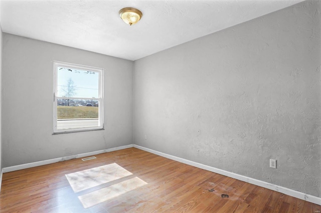 empty room with visible vents, baseboards, and wood finished floors