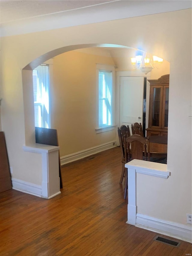 dining area with baseboards, wood finished floors, visible vents, and arched walkways