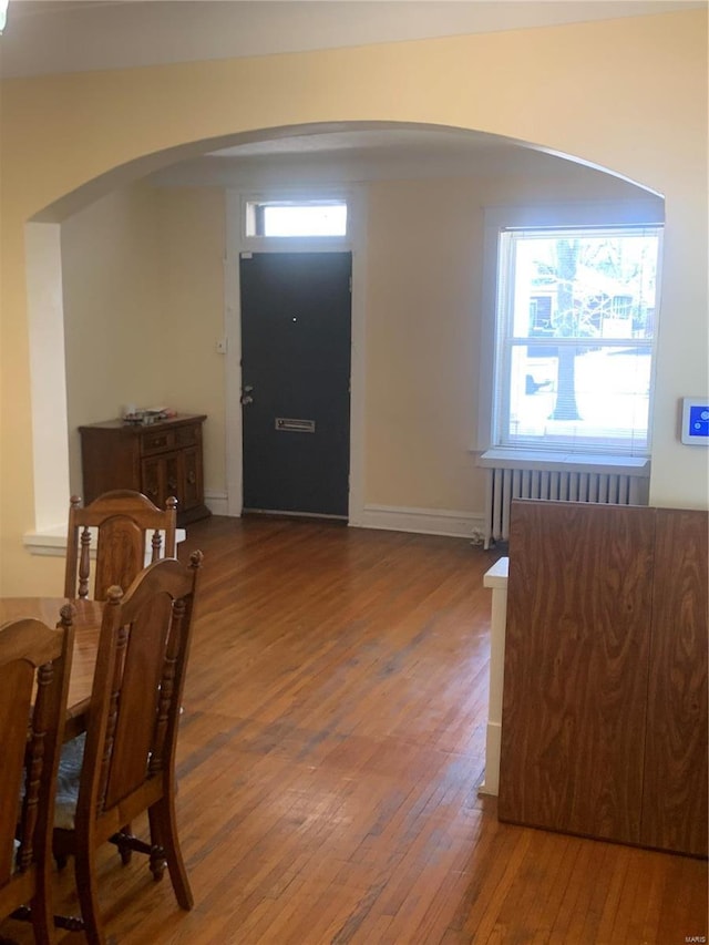 entrance foyer with arched walkways and hardwood / wood-style floors