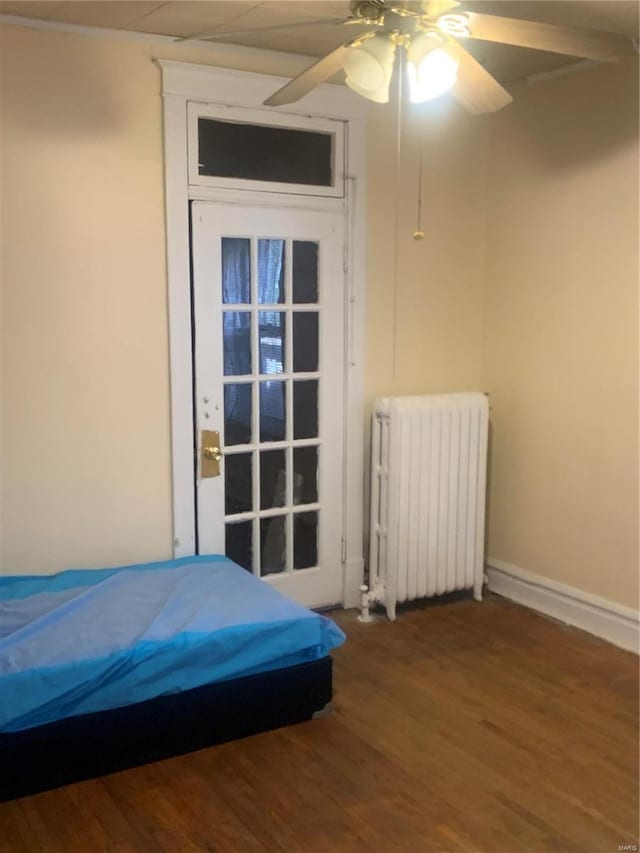 bedroom with ceiling fan, baseboards, radiator, and wood finished floors