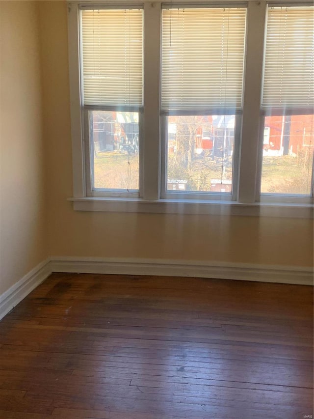 spare room featuring baseboards and wood-type flooring