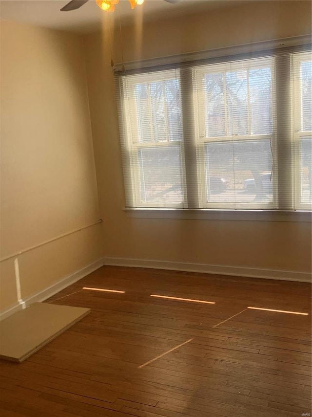 empty room with plenty of natural light, wood finished floors, and baseboards