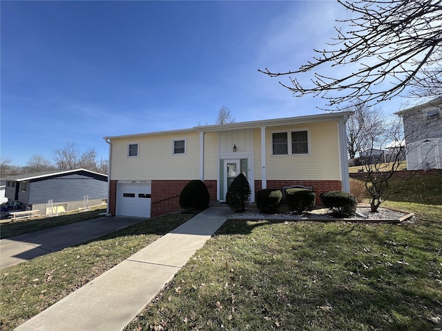 split foyer home with a front yard, a garage, brick siding, and concrete driveway