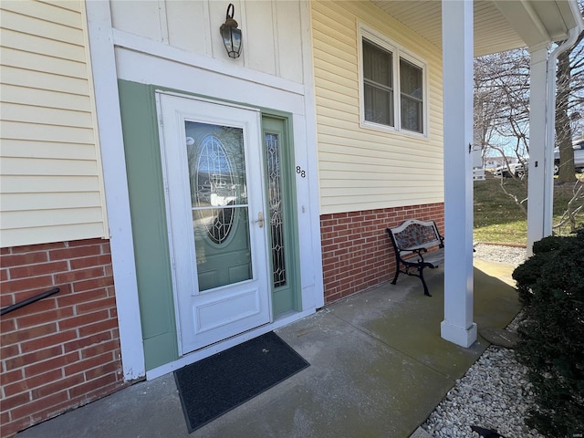 property entrance featuring brick siding and covered porch