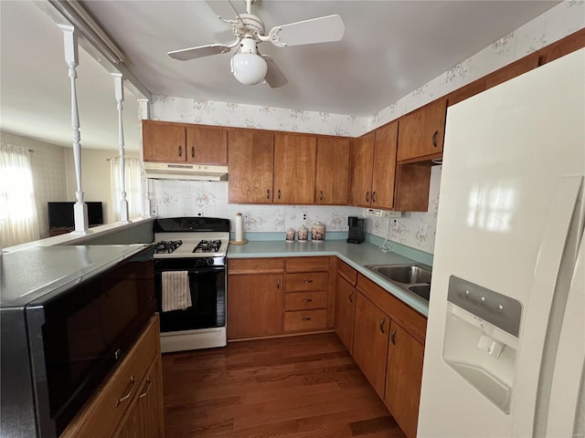 kitchen with gas stove, wallpapered walls, under cabinet range hood, white fridge with ice dispenser, and black microwave