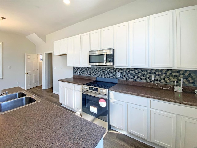 kitchen featuring dark countertops, decorative backsplash, white cabinetry, and stainless steel appliances