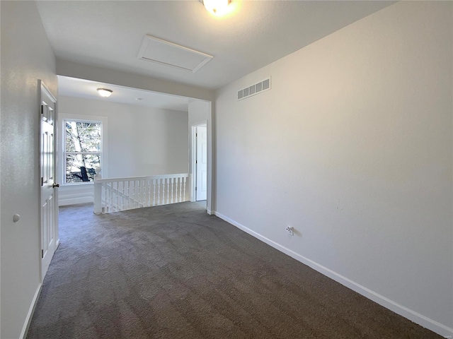 empty room featuring visible vents, carpet flooring, attic access, and baseboards