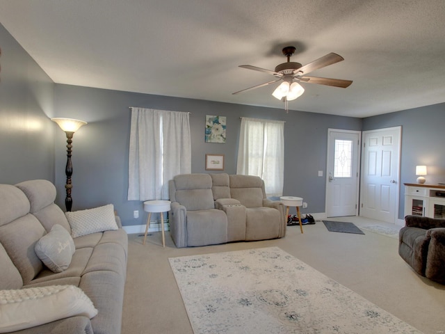 living area with light colored carpet, a textured ceiling, baseboards, and ceiling fan