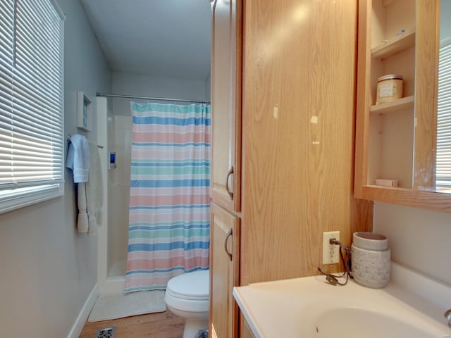 bathroom featuring vanity, wood finished floors, baseboards, a healthy amount of sunlight, and toilet