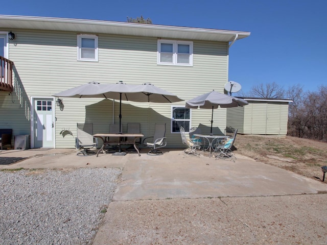 rear view of property with a patio area, a storage shed, outdoor dining area, and an outdoor structure