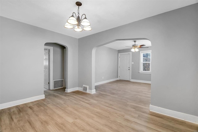 spare room with arched walkways, visible vents, and light wood finished floors