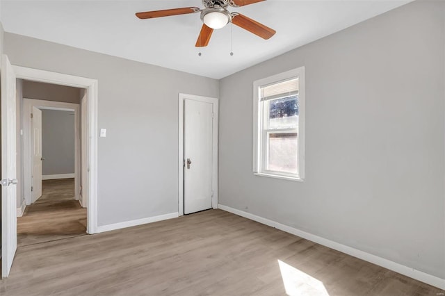 unfurnished bedroom with ceiling fan, baseboards, and light wood-type flooring