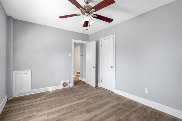 unfurnished bedroom featuring visible vents, a ceiling fan, baseboards, and wood finished floors