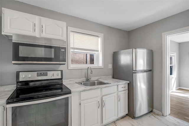 kitchen featuring a sink, light countertops, marble finish floor, and stainless steel appliances