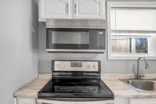 kitchen with white cabinets, stainless steel appliances, light countertops, and a sink