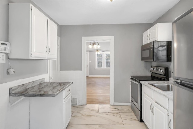 kitchen with stainless steel appliances, marble finish floor, white cabinets, and light countertops