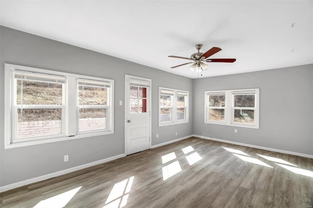 empty room with ceiling fan, baseboards, and wood finished floors