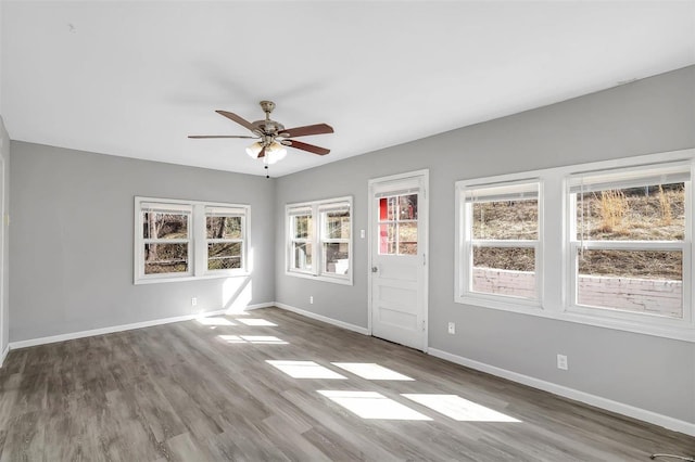 empty room with wood finished floors, baseboards, and ceiling fan