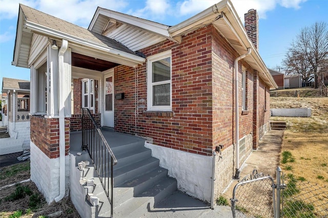 exterior space featuring brick siding, a chimney, and fence