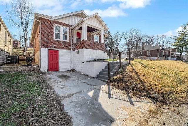 view of front of house with brick siding, cooling unit, and a front lawn