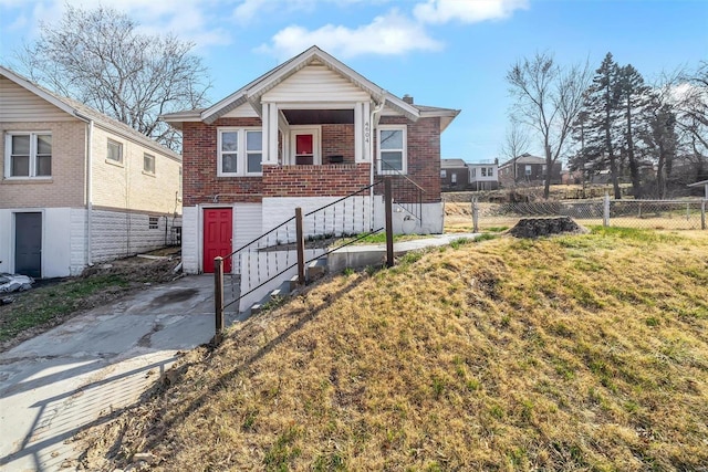 view of front of property with a front lawn, fence, and brick siding