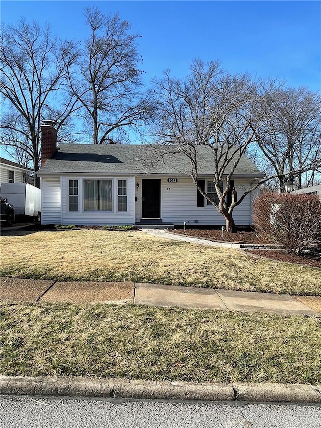 single story home featuring a chimney and a front lawn