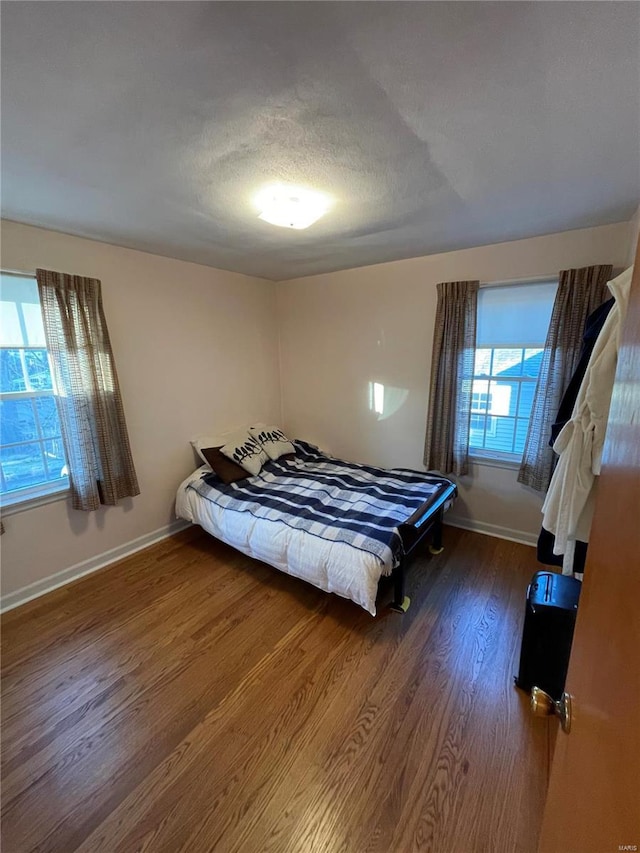 unfurnished bedroom with baseboards, a textured ceiling, and wood finished floors