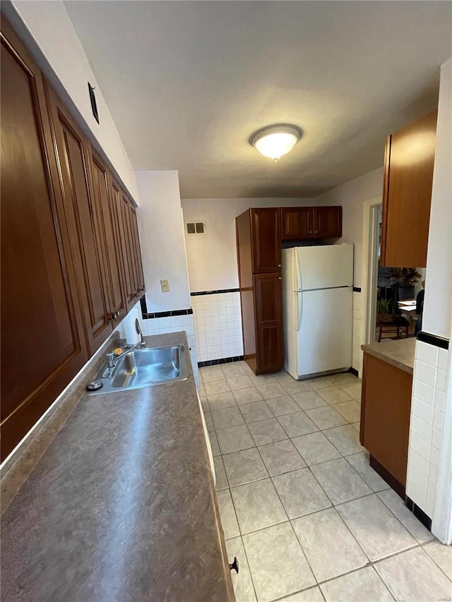 kitchen featuring a sink, visible vents, light tile patterned floors, and freestanding refrigerator