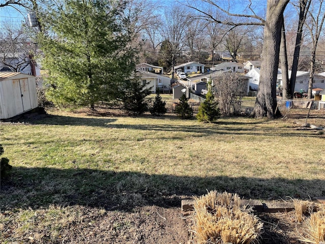 view of yard with a residential view, an outbuilding, a storage shed, and fence