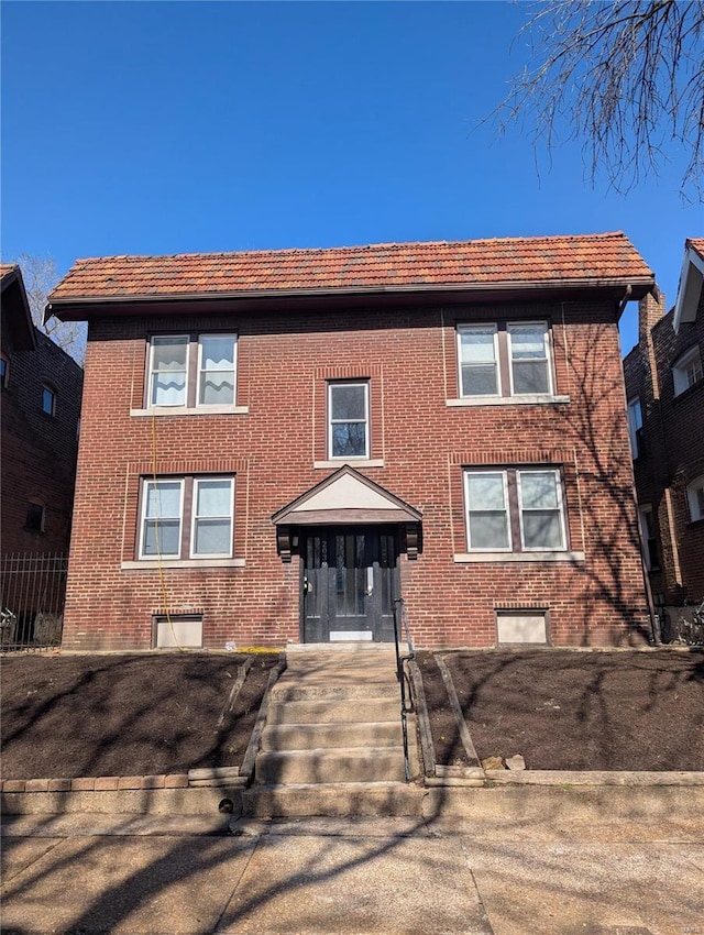 multi unit property with brick siding and a tile roof