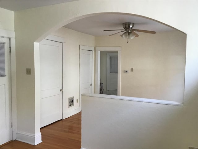 hall featuring baseboards, arched walkways, and wood finished floors