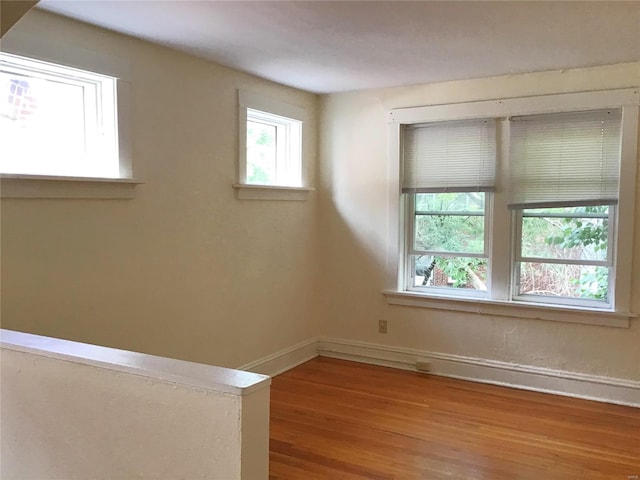 spare room featuring wood finished floors, baseboards, and a healthy amount of sunlight