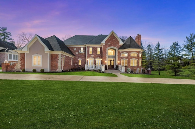 view of front facade featuring brick siding, a chimney, concrete driveway, and a front lawn