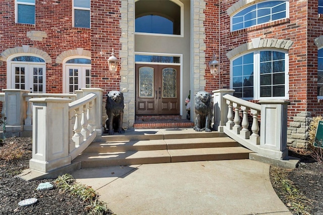 view of exterior entry featuring french doors and brick siding