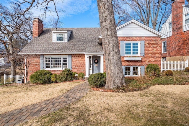 view of front facade featuring fence, a shingled roof, a chimney, a front lawn, and brick siding