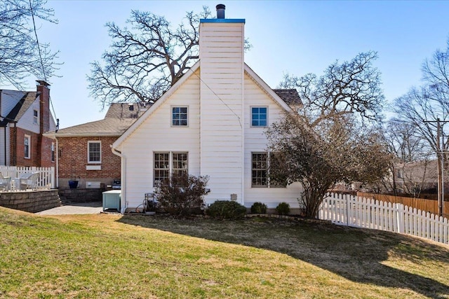 rear view of property featuring a patio, a chimney, a yard, and fence