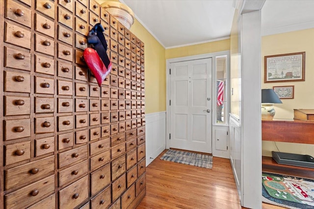 entrance foyer featuring crown molding, wood finished floors, and a wainscoted wall