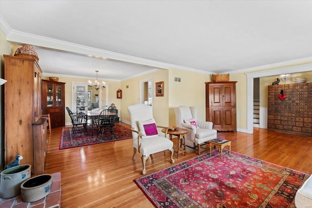 living room with ornamental molding, visible vents, light wood finished floors, and a chandelier