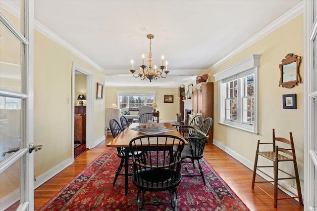 dining space featuring light wood-type flooring, baseboards, a notable chandelier, and ornamental molding