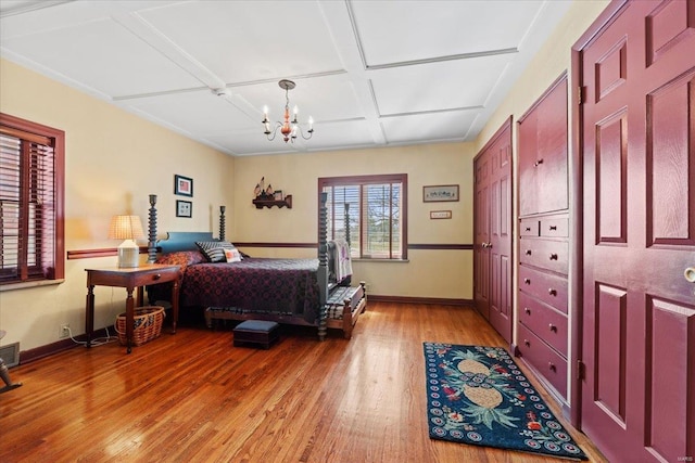 bedroom featuring a notable chandelier, baseboards, light wood-type flooring, and coffered ceiling