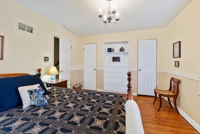 bedroom with visible vents, baseboards, an inviting chandelier, and wood finished floors