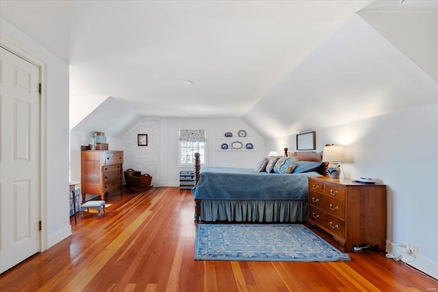 bedroom featuring baseboards, lofted ceiling, and wood finished floors