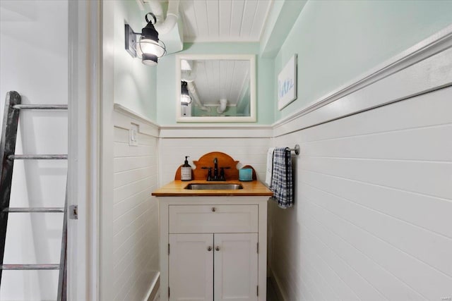 bathroom featuring a wainscoted wall, vanity, and tile walls